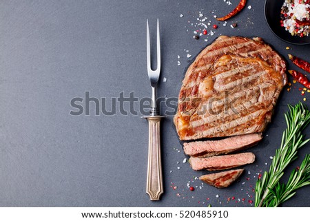 Grilled sliced beef steak on slate stone table. Top view. Copy space