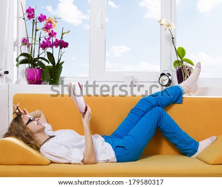 Lecture time/ Young woman reading a book on the couch