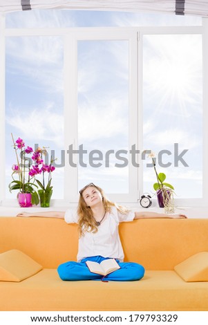 Readers imagination / Woman day dreaming with a book on her legs in front of a big window  Edit