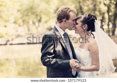 Beautiful portrait of the bride and groom kissing in the park and holding hands.