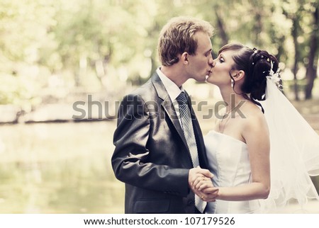 Beautiful portrait of the bride and groom kissing in the park and holding hands.