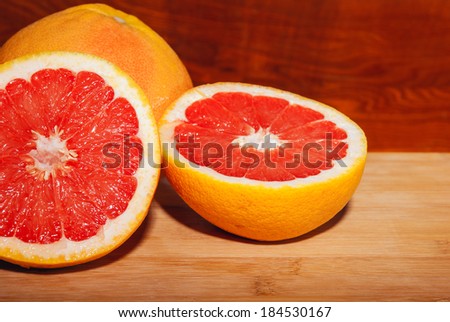 Slices of ripe red grapefruit on wooden board.