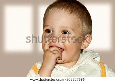 Small smiling baby with finger in the nose.