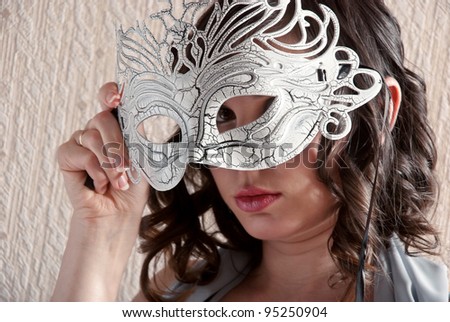 Pretty woman with a mask in his hand. Focus on the mask.