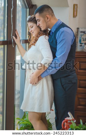 The young loving couple embraces and are by the big window. Wedding