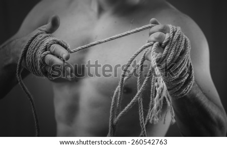 Close-up of a young Thai boxer hands hemp ropes are wrapped before the fight or training. Black and white style