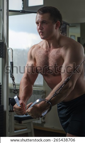 Young man at the gym exercise on the pectoral muscles, the reduction in the hands of crossover