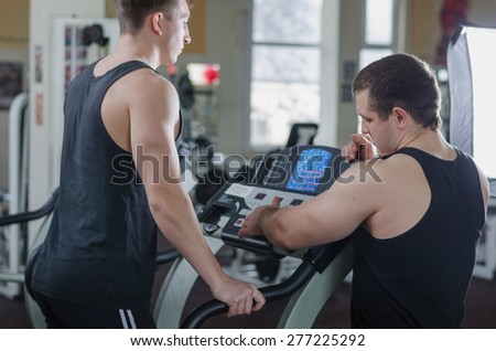 The coach helps the athlete on a treadmill at the gym