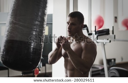 Young athlete in motion with blurred hands on training with a boxing bag gym. Toning