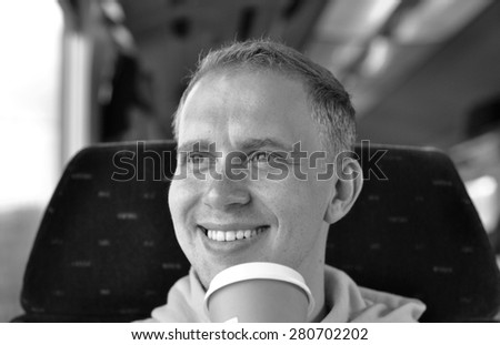 A young guy traveling by the train with cup of coffee - black and white photo
