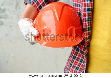 Hand of worker with red hard-hat