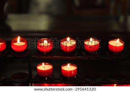Many red votive candles light the darkness in church