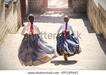 Two Korean Girls dressed in traditional dress running down stairs in Seoul street
