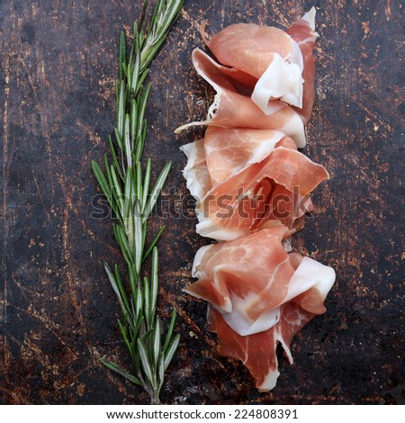 Prosciutto and rosemary on brown rustic background