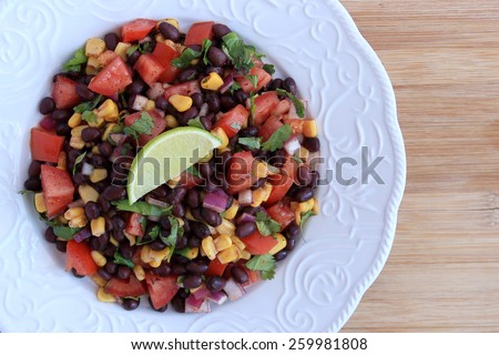 Black bean salad in white plate on wood background