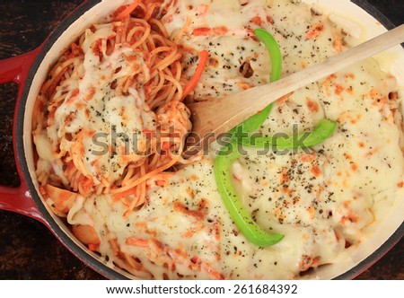 Spaghetti with grated cheese, baked in the oven, in red dutch oven