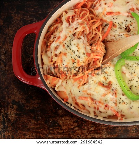 Spaghetti with grated cheese, baked in the oven, in red dutch oven