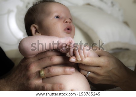 an infant being held by a male and female pair of hands