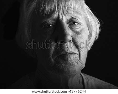 a distressed older lady in dramatic low key black and white