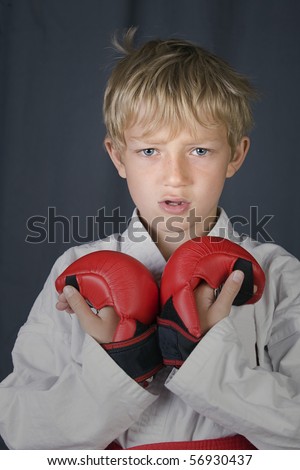 young blonde boy in karate outfit, red belt and pads
