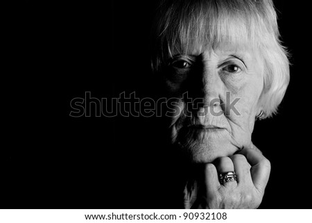 powerful monochrome low key image of a sad elderly woman