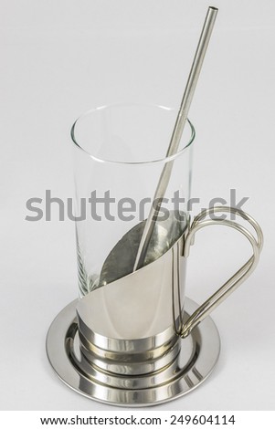 Side view of empty glass with metallic glass-holder and spoon isolated on white background