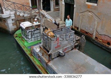 Venice, Italy - August 21, 2015: Two workers on a boat taking out the garbage to keep Venice clean. Specially constructed boat for garbage collection replaced in Venice the classic garbage truck.