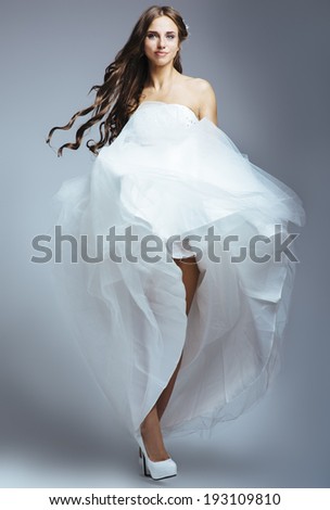 Growth portrait of a young beautiful woman with long flowing hair, dressed in a white wedding dress and white shoes