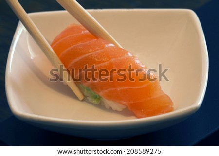 Salmon sushi nigiri in bamboo sticks into a plate