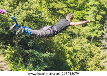 a man doing bungee jumping with a forest in background