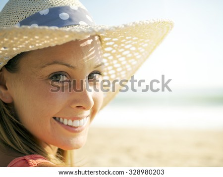 happy girl smiling portrait in the beach  wearing a picture hat with the sea and horizon in the background