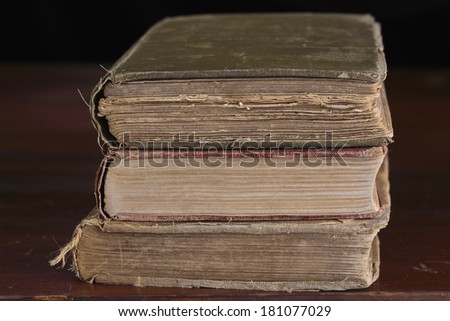 Eye level with a stack of three well worn vintage books on an old table