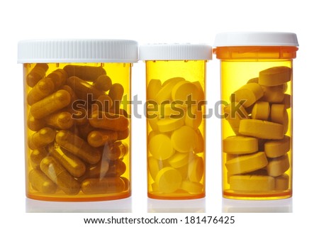 Three prescription medication bottles setting on a glass medicine cabinet shelf. Containers hold capsules, caplets, and tablets.