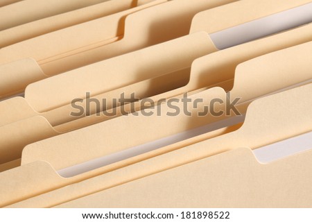 Blank file folder tabs in a filing cabinet drawer. Primary focus on tabs near the front of the image.