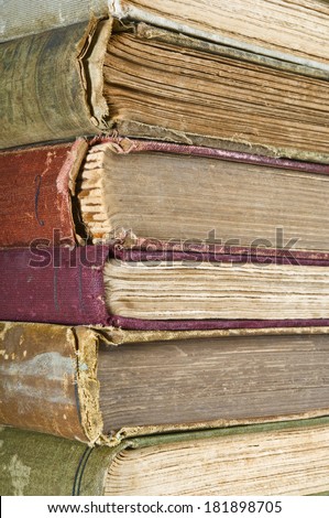 Stack of old books showing much wear. Tattered pages and worn Bindings. Focus on book corners.