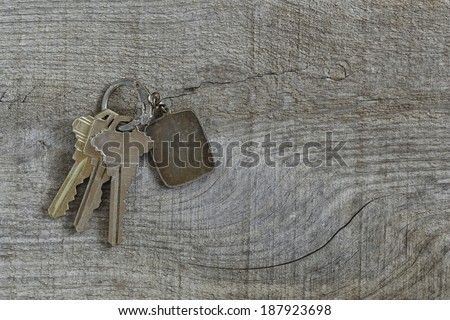 Key ring with three house or door keys on weathered wood.