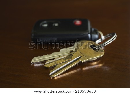 A close-up shot of a remote key fob or an automobile and three metal door keys on a key ring.