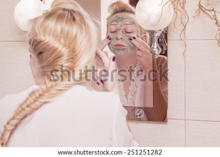 Girl puts a mask on his face in the mirror
