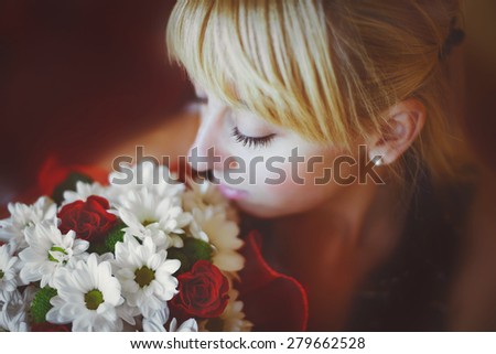 Girl looks at a bouquet of roses and daisies