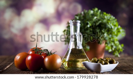 Bottles of olive oil, bunch of tomateos, fresh basil and olives
