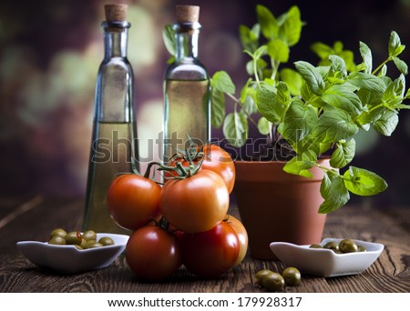 Bottles of olive oil, bunch of tomateos, fresh basil and olives