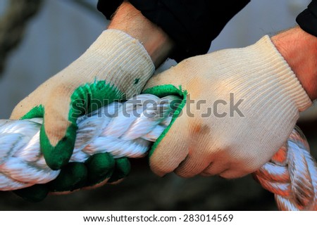 human hands in gloves pull the mooring rope