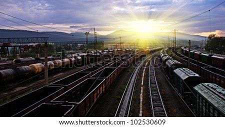 railway station, different trains and wagons at sunset with dramatic sky