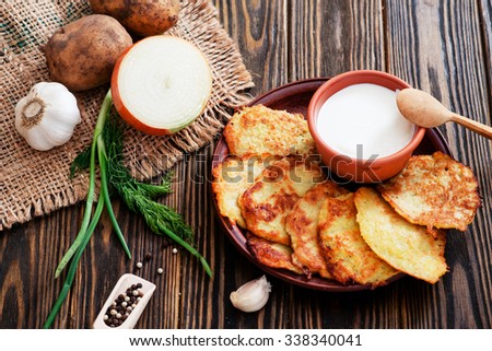 national russian and ukrainian cuisine, \
potato pancakes with sour cream , herbs , garlic and spices on a wooden background