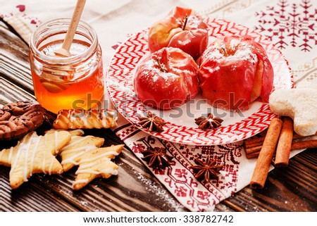 winter dessert , baked apples in powdered sugar , honey , cinnamon , spices and Christmas cookies on a wooden background