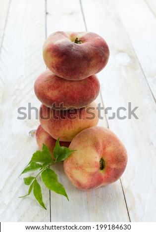 Saturn peaches, Donut, Fig, UFO or flat peaches with leaves on white wood boards