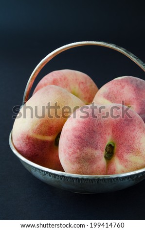Saturn peaches or donut, UFO, flat peaches on black background in silver bowl