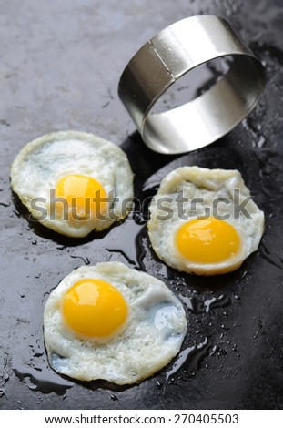 Fried eggs with metallic circle, selective focus