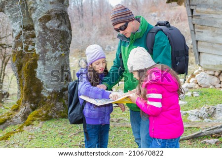 Family hiking in countryside looking for directions on the map.