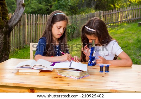 Portrait of two happy female young students on campus sitting casually at an outdoor table.